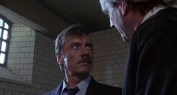 Movie still from “A Fish Called Wanda” (1988), directed by Charles Crichton – A man in a suit and tie standing next to another man in a suit and tie; Close Up shot, Low angle