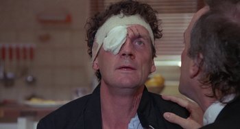 Movie still from “A Fish Called Wanda” (1988), directed by Charles Crichton – A man with bandage on his head and a bandage on his eye; Close Up shot, High angle