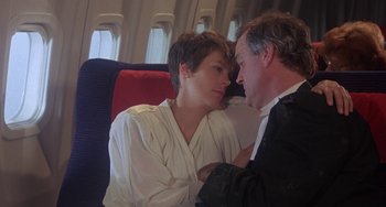 Movie still from “A Fish Called Wanda” (1988), directed by Charles Crichton – A man and a woman sitting next to each other on a plane; Medium shot, Low angle