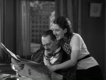 Movie still from “A Free Soul” (1931), directed by Clarence Brown – A man and a woman are reading a newspaper together; Medium shot, High angle
