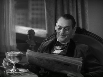Movie still from “A Free Soul” (1931), directed by Clarence Brown – A man sitting at a table reading a newspaper; Close Up shot, High angle