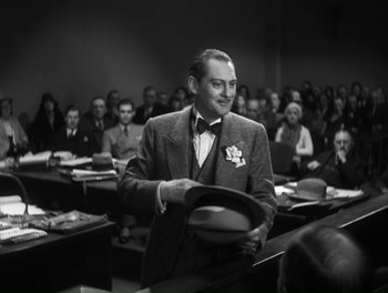 Movie still from “A Free Soul” (1931), directed by Clarence Brown – An old photo of a man holding a hat in front of a crowd; Medium shot, Low angle