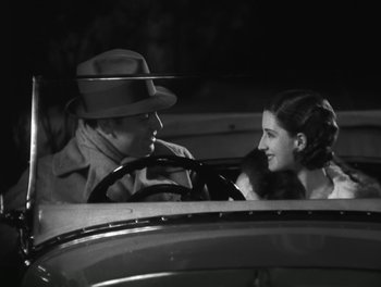 Movie still from “A Free Soul” (1931), directed by Clarence Brown – A man and a woman in the driver's seat of an old car; Medium shot, High angle