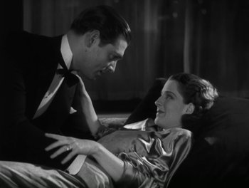 Movie still from “A Free Soul” (1931), directed by Clarence Brown – A man and a woman sitting on a couch together; Medium shot, High angle
