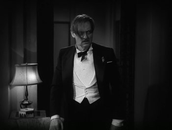 Movie still from “A Free Soul” (1931), directed by Clarence Brown – A man in a tuxedo standing next to a lamp; Medium shot, Low angle