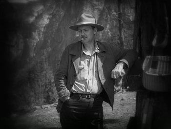 Movie still from “A Free Soul” (1931), directed by Clarence Brown – A black and white photo of a man wearing a hat; Medium shot, Low angle