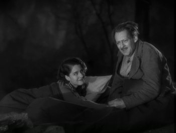Movie still from “A Free Soul” (1931), directed by Clarence Brown – A man and a woman sitting next to each other on the ground; Medium shot, High angle
