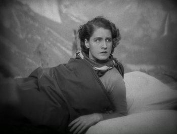 Movie still from “A Free Soul” (1931), directed by Clarence Brown – An old black and white photo of a woman laying on a couch; Medium shot, Low angle