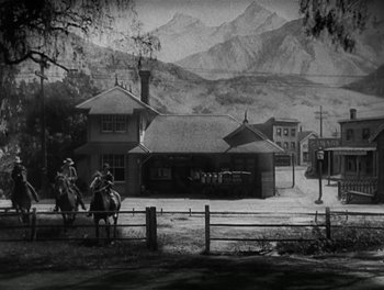 Movie still from “A Free Soul” (1931), directed by Clarence Brown – Two men on horses in front of a building; Extreme Wide shot, Low angle