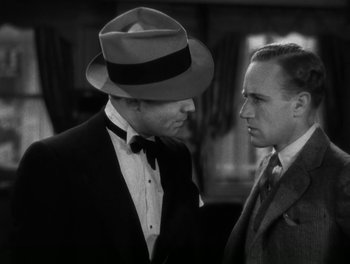 Movie still from “A Free Soul” (1931), directed by Clarence Brown – A man in a suit and a hat talking to another man in a suit and a hat; Close Up shot, Over the shoulder angle