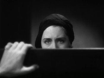Movie still from “A Free Soul” (1931), directed by Clarence Brown – A woman with a head covering looking over a ledge; Close Up shot, Over the shoulder angle