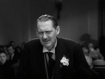 Movie still from “A Free Soul” (1931), directed by Clarence Brown – An older man wearing a suit and tie with a flower in his lapel; Close Up shot, Low angle