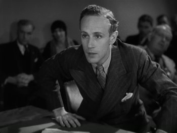 Movie still from “A Free Soul” (1931), directed by Clarence Brown – A man in a suit and tie sitting at a table; Close Up shot, High angle