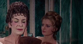 Movie still from “A Funny Thing Happened on the Way to the Forum” (1966), directed by Richard Lester – A woman looking in the mirror while another looks in the mirror; Close Up shot, Over the shoulder angle