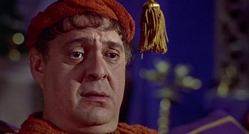 Movie still from “A Funny Thing Happened on the Way to the Forum” (1966), directed by Richard Lester – A person wearing a hat; Close Up shot, Over the shoulder angle