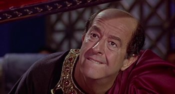Movie still from “A Funny Thing Happened on the Way to the Forum” (1966), directed by Richard Lester – An older man wearing a gold chain around his neck; Close Up shot, Low angle