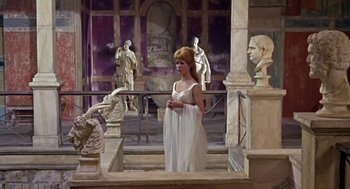 Movie still from “A Funny Thing Happened on the Way to the Forum” (1966), directed by Richard Lester – A woman standing in front of a group of statues; Wide shot, Low angle