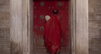 Movie still from “A Funny Thing Happened on the Way to the Forum” (1966), directed by Richard Lester – A woman dressed in roman clothes standing in front of a door; Wide shot, High angle