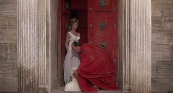 Movie still from “A Funny Thing Happened on the Way to the Forum” (1966), directed by Richard Lester – A man kneeling down next to a woman in a white dress; Wide shot, Low angle