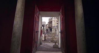 Movie still from “A Funny Thing Happened on the Way to the Forum” (1966), directed by Richard Lester – An open door leading to a courtyard with a fountain; Extreme Wide shot, Low angle