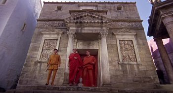 Movie still from “A Funny Thing Happened on the Way to the Forum” (1966), directed by Richard Lester – A group of men standing in front of a building; Extreme Wide shot, Low angle