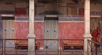 Movie still from “A Funny Thing Happened on the Way to the Forum” (1966), directed by Richard Lester – A blue door and two benches in front of a red wall; Extreme Wide shot, High angle