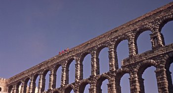 Movie still from “A Funny Thing Happened on the Way to the Forum” (1966), directed by Richard Lester – A group of people standing on the side of an ancient roman aqueduct; Extreme Wide shot, Low angle