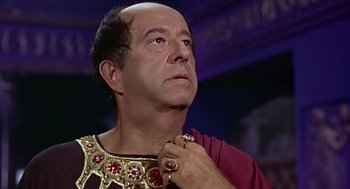 Movie still from “A Funny Thing Happened on the Way to the Forum” (1966), directed by Richard Lester – An older man wearing a red and gold roman costume; Close Up shot, Low angle
