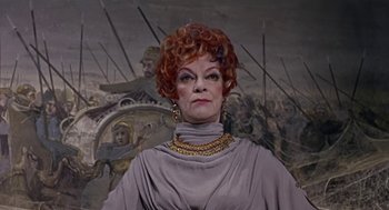 Movie still from “A Funny Thing Happened on the Way to the Forum” (1966), directed by Richard Lester – An older woman with red hair and a large necklace; Close Up shot, Low angle