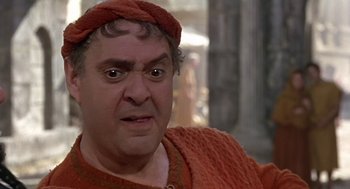 Movie still from “A Funny Thing Happened on the Way to the Forum” (1966), directed by Richard Lester – An older man wearing a red sweater and a red hat; Close Up shot, Over the shoulder angle
