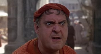 Movie still from “A Funny Thing Happened on the Way to the Forum” (1966), directed by Richard Lester – A man with a red hat and sweater on; Close Up shot, Low angle