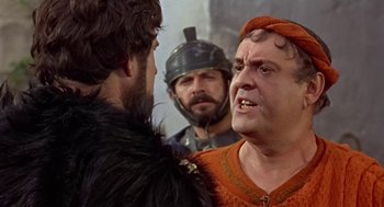 Movie still from “A Funny Thing Happened on the Way to the Forum” (1966), directed by Richard Lester – Two men in medieval garb and one is wearing a helmet; Close Up shot, Over the shoulder angle