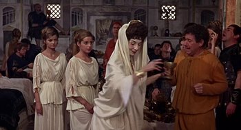 Movie still from “A Funny Thing Happened on the Way to the Forum” (1966), directed by Richard Lester – A group of people dressed in ancient roman clothing; Medium shot, Over the shoulder angle