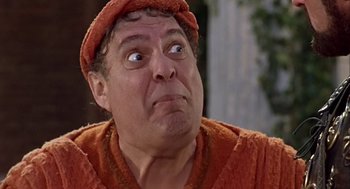 Movie still from “A Funny Thing Happened on the Way to the Forum” (1966), directed by Richard Lester – A person wearing a robe and a hat; Close Up shot, Low angle