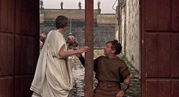 Movie still from “A Funny Thing Happened on the Way to the Forum” (1966), directed by Richard Lester – Two men in roman garb standing next to each other; Wide shot, Over the shoulder angle