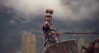 Movie still from “A Funny Thing Happened on the Way to the Forum” (1966), directed by Richard Lester – A man in a roman soldier costume points to the sky; Medium shot, Low angle