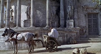 Movie still from “A Funny Thing Happened on the Way to the Forum” (1966), directed by Richard Lester – A man sitting on a cart next to a horse; Wide shot, Low angle