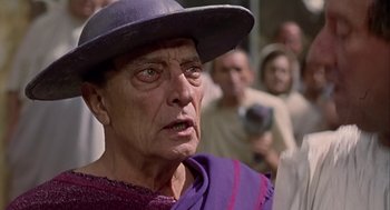 Movie still from “A Funny Thing Happened on the Way to the Forum” (1966), directed by Richard Lester – An old man wearing a purple outfit and a purple hat; Close Up shot, Low angle