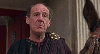 Movie still from “A Funny Thing Happened on the Way to the Forum” (1966), directed by Richard Lester – An older man wearing a black and gold robe; Close Up shot, Low angle