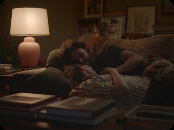 Movie still from “A Ghost Story” (2017), directed by David Lowery – A man and a woman laying on a couch in a living room; Medium shot, Over the shoulder angle