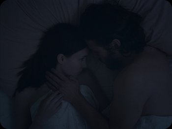Movie still from “A Ghost Story” (2017), directed by David Lowery – A man and a woman laying in a bed together; Close Up shot, High angle