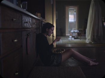 Movie still from “A Ghost Story” (2017), directed by David Lowery – A woman sitting on the floor eating a bowl of cereal; Medium shot, High angle