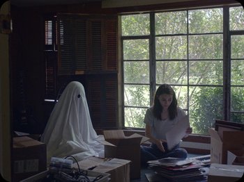 Movie still from “A Ghost Story” (2017), directed by David Lowery – A woman sitting on the floor in front of a window; Medium shot, Over the shoulder angle