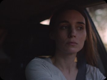 Movie still from “A Ghost Story” (2017), directed by David Lowery – A woman sitting in the back seat of a car; Close Up shot, Over the shoulder angle