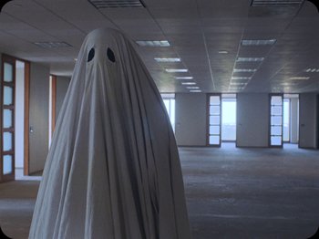 Movie still from “A Ghost Story” (2017), directed by David Lowery – An image of a ghost in an empty room; Wide shot, High angle
