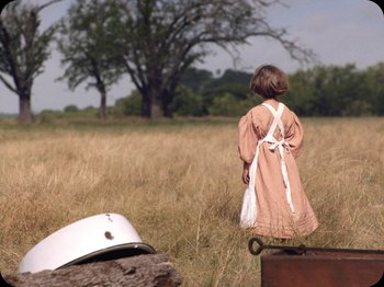 Movie still from “A Ghost Story” (2017), directed by David Lowery – A little girl in a dress standing in a field; Wide shot, Low angle