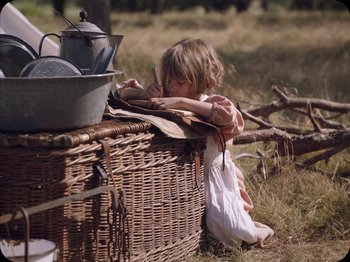 Movie still from “A Ghost Story” (2017), directed by David Lowery – A little girl sitting on the ground next to a basket; Medium shot, High angle