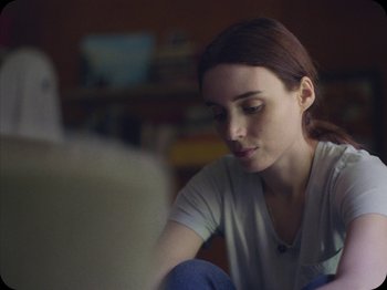 Movie still from “A Ghost Story” (2017), directed by David Lowery – A woman sitting in front of a laptop computer; Close Up shot, Over the shoulder angle