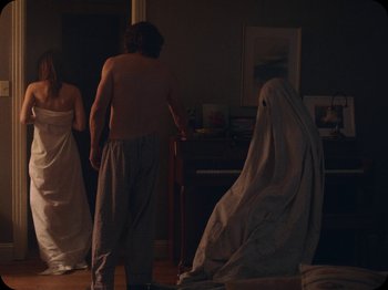 Movie still from “A Ghost Story” (2017), directed by David Lowery – A man standing next to a woman in a white dress; Medium shot, Over the shoulder angle
