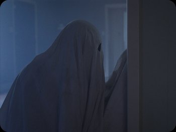 Movie still from “A Ghost Story” (2017), directed by David Lowery – A person with a white sheet covering their face; Medium shot, Low angle